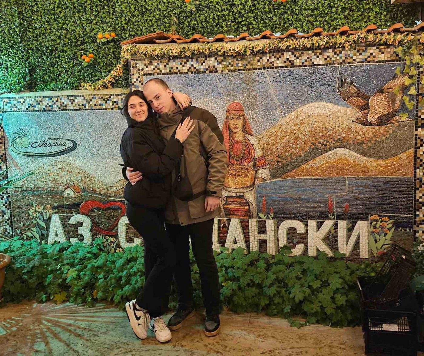 Us hugging in front of a mosaic wall